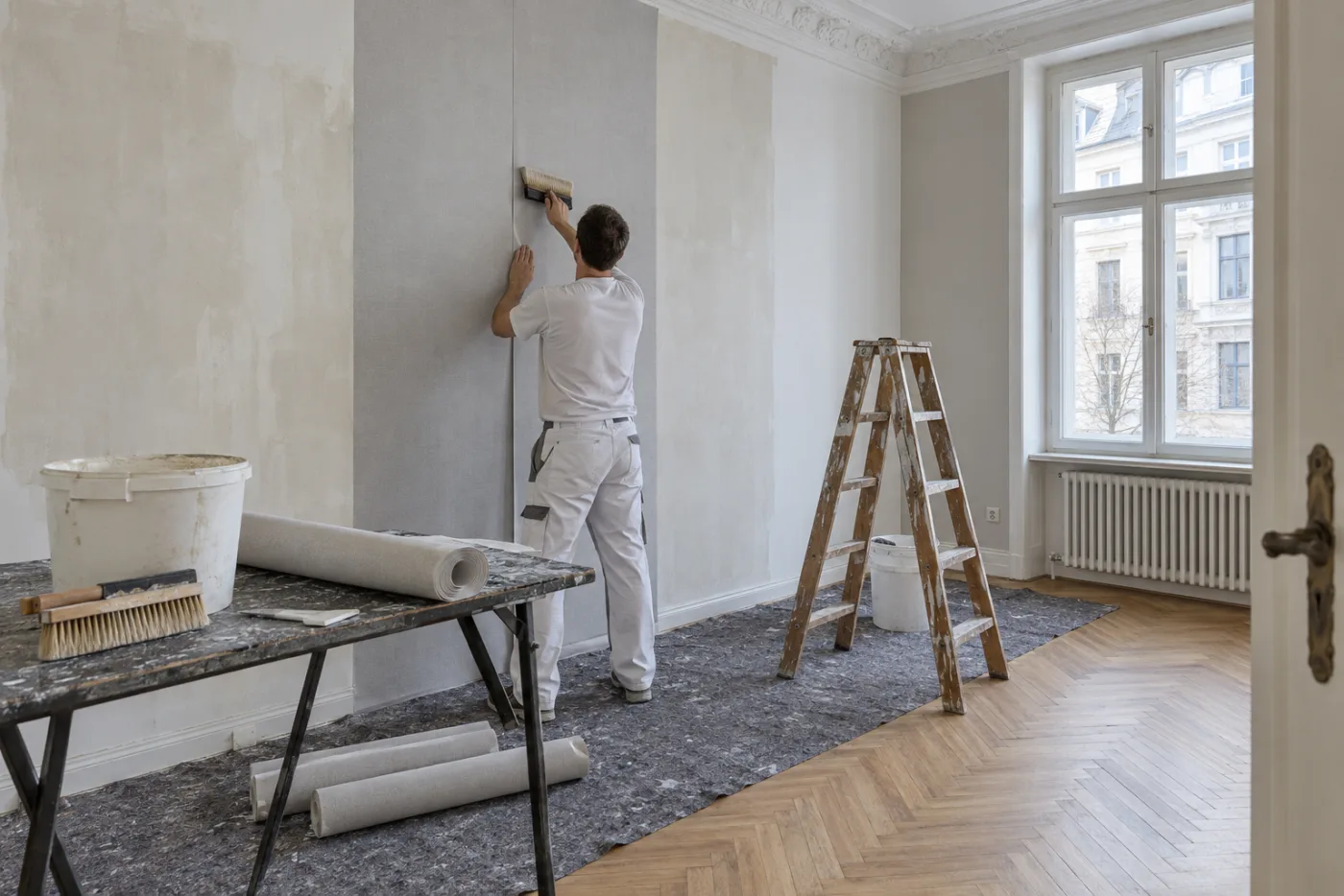 KI-generiertes Symbolbild: Maler tapeziert einen hohen Raum in einer Altbauwohnung eines Gelsenkirchener Mehrfamilienhauses.